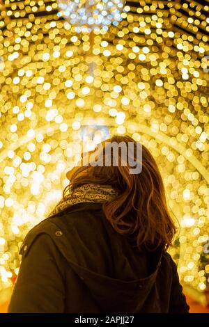 Mädchen von hinten gesehen mit weihnachtslichtern im Hintergrund Stockfoto