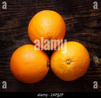 Anordnung ganzer Orangen auf dunklem Hintergrund. Kleine Gruppe von Objekten. Stockfoto