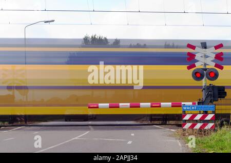 Holländischer Zug, der einen Bahnübergang passiert, verwischt durch Bewegung Stockfoto