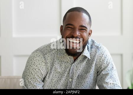 Der afrikanische bärtige Mann, der die Kamera zum Lachen betrachtet, fühlt sich überglücklich an Stockfoto