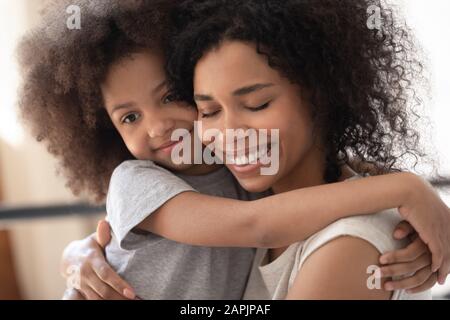 Nahaufnahme des Porträts der liebenden afrikanischen Tochter umarmt Mutter Stockfoto