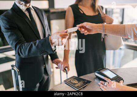 Nahaufnahme von Geschäftsleuten erfolgt beim Check-In an der Rezeption per Kreditkarte. Geschäftsreisekonzept. Stockfoto