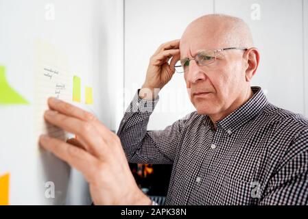 Ältere Mann an Noten suchen. Forgetful Senior mit Demenz, Memory Problem, Gesundheit Konzept Stockfoto