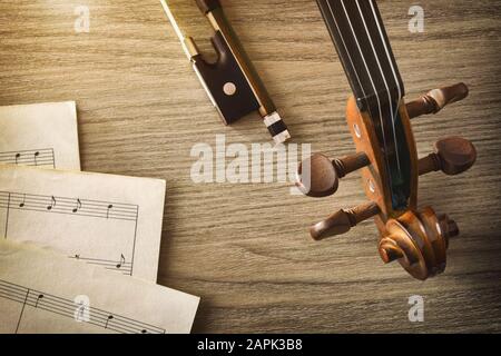 Geigenpegbox und Schleife mit Noten auf Holztisch Vintage. Draufsicht. Horizontale Zusammensetzung. Stockfoto