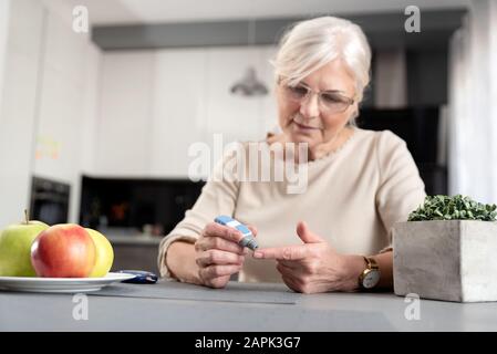 Ältere Frau, ihren Blutzuckerspiegel zu überprüfen. Health Care Diabetes Konzept Stockfoto