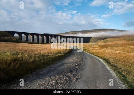 An einem nebligen Wintermorgen überquert ein Sprinter-Personenzug das Ribblehead Viaduct auf der Bahnstrecke Settle-Carlisle, Yorkshire Dales National Park. Stockfoto