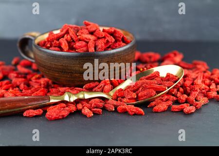 Goji-Beeren in einer Tasse und Vintage-Löffel auf grauem Schieferhintergrund. Selektiver Fokus Stockfoto