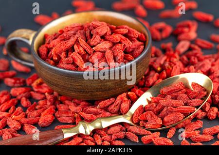 Goji-Beeren im Becher mit Vintage-Löffel auf grauem Schiefer. Ansicht von oben, selektiver Fokus Stockfoto