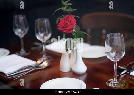Rote Rose in einer weißen Porzellanvase auf einem servierten Tisch in einem Restaurant Stockfoto