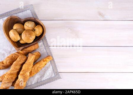 Hausgemachte frisch gebackene Brotstangen mit Käse und Knoblauchbrötchen auf hellem Holzhintergrund, mit Platz für Text, Draufsicht Stockfoto