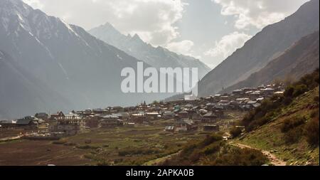 Ein weiter Blick auf das Dorf Chitkul vor dem Hintergrund der hohen schneebedeckten Berge des Himalayas, die sie umgeben. Stockfoto