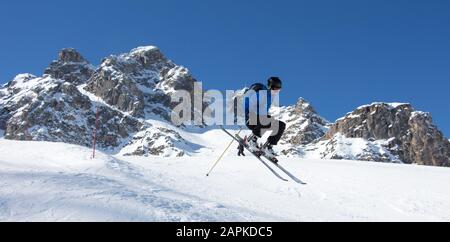 Skifahrer springen vor den Felsenbergen Meribel Sonne Schnee Berglandschaft Frankreich alpen 3 vallees Stockfoto