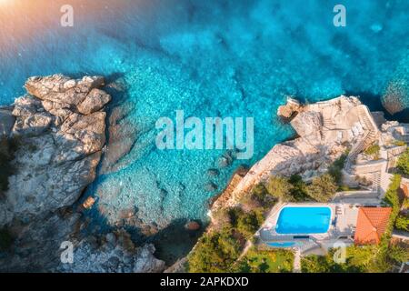 Blick auf den felsigen Strand, den Pool, die grünen Bäume und das blaue Meer Stockfoto