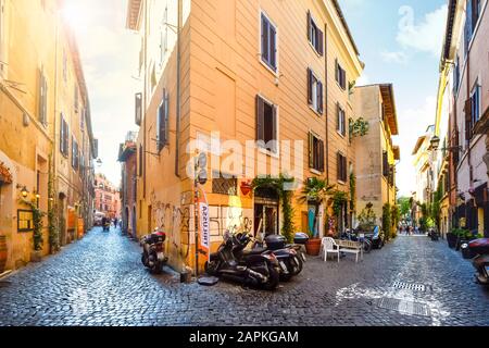 Malerische, farbenfrohe Kopfsteinpflaster mit geparkten Motorrädern und Geschäften im Trastevere Viertel von Rom Italien. Stockfoto