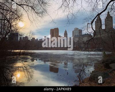 Wolkenkratzer aus New York spiegelten sich bei Sonnenuntergang in Iced Lake wider Stockfoto