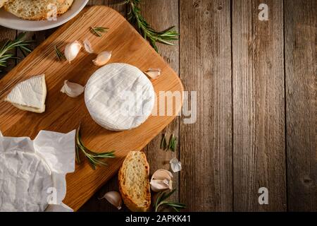 Camembert Käse, Knoblauch, Rosmarin und Brot auf Holzschneidebrett Stockfoto