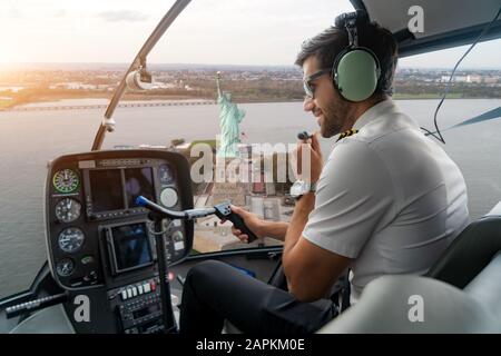 Helikopter-Cockpit mit pilot Arm und Kontrolle-Konsole in der Kabine auf Liberty Island und die berühmte Statue of Liberty Denkmal Wahrzeichen von New York Stockfoto