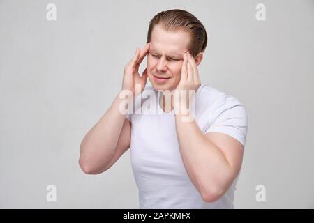Der junge Mann berührt mit den Händen den Kopf und frostet mit Kopfschmerzen stark. Nahaufnahme. Stockfoto