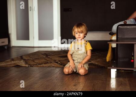 Kleiner Junge, der auf dem Teppich im Haus sitzt Stockfoto