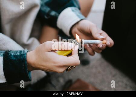 Nahaufnahme der Hände einer Frau, die ein Marihuana-Joint beleuchten Stockfoto