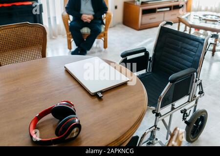 Kopfhörer und Laptop mit usb-Stick auf dem Tisch im Wohnzimmer des Seniors Stockfoto