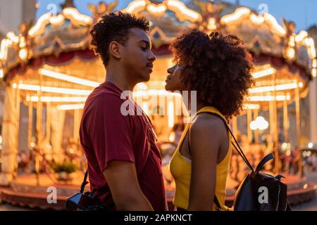 Liebevolles junges Touristenpaar auf einem beleuchteten Karussell in der Stadt in der Abenddämmerung, Florenz, Italien Stockfoto