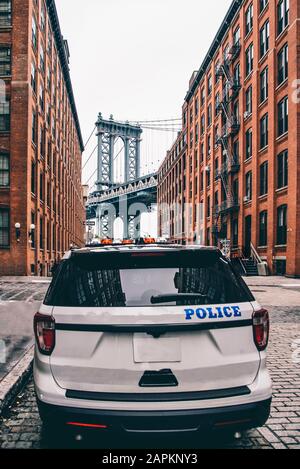 USA, New York, New York City, Polizeiauto auf der Straße mit Manhattan Bridge im Hintergrund Stockfoto