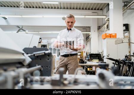 Geschäftsmann, der ein Tablet in einer Fabrik verwendet Stockfoto