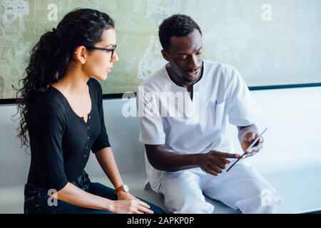 Zahnärztin mit Tablette spricht mit weiblicher Patientin in der Zahnchirurgie Stockfoto