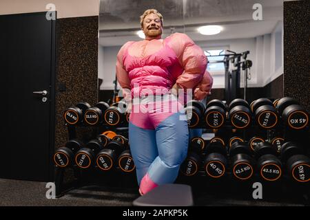 Stolzer Mann, der im Fitnessstudio ein pinkfarbenes Bodybuilder-Kostüm trägt Stockfoto