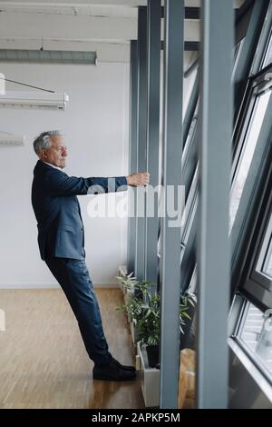 Leitender Geschäftsmann, der den Träger im Amt hält Stockfoto