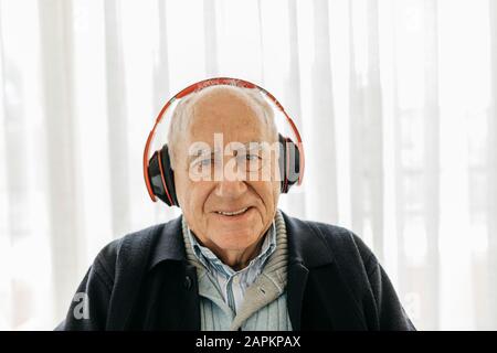 Porträt eines lächelnden Seniors, der Musik mit Kopfhörern hört Stockfoto