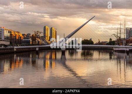 Schöner Blick auf den Sonnenuntergang auf die moderne Brücke und die Gebäude in Puerto Madero, Buenos Aires, Argentinien Stockfoto