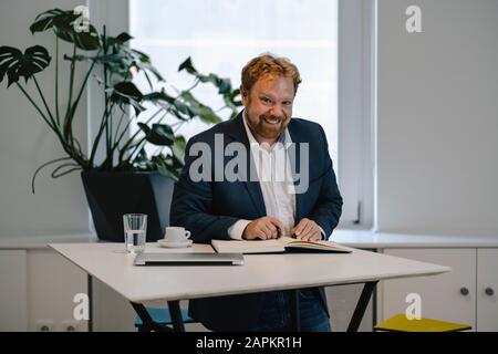 Porträt eines lächelnden Geschäftsmannes, der Notizen am Tisch nimmt Stockfoto