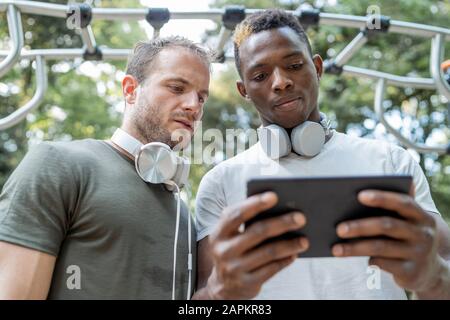 Freunde, die eine Pause vom Trainieren beim betrachten von Phablet haben Stockfoto