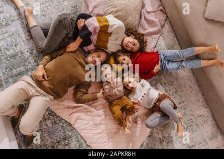 Glückliche Familie mit drei Töchtern, die zu Hause auf Decken liegen Stockfoto