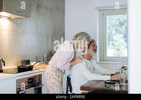 Liebevoll reifes Paar am Tisch in der Küche zu Hause Stockfoto