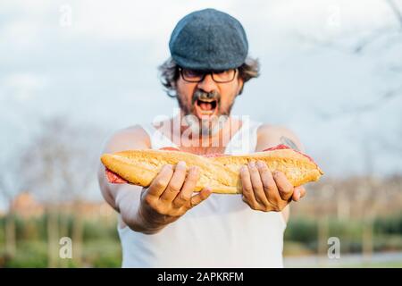 Mann hält Sandwich und schreit Stockfoto