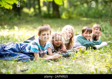 Schulkinder kampieren im Wald und liegen in Schlafsäcken Stockfoto