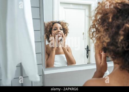 Junge Frau im Bad mit Gesichtscreme Stockfoto