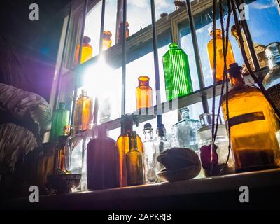 Viele Gläser und Flaschen der alten Apotheke auf dem Regal mit der hellen Sonne im Hintergrund Stockfoto