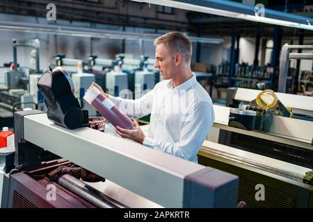 Mann in weißem Hemd in einer Fabrik, die das Produkt untersucht Stockfoto