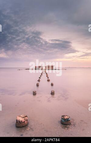 Spanien, Murcia, Santiago de la Ribera, Holzpfosten in ruhiger See bei Sonnenuntergang Stockfoto