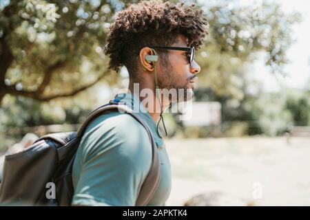 Junger Mann mit Ohrhörern in einem Park Stockfoto