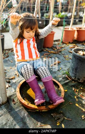 Kleines Mädchen, das Wellington Stiefel trägt, spielt in der Kinderkrippe Stockfoto