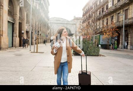 Lächelnde junge Frau mit Koffer und Kamera in der Stadt unterwegs, Barcelona, Spanien Stockfoto