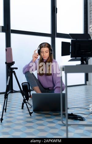 Porträt der jungen Frau, die in einem Studio mit Laptop und Smartphone aufgenommen wurde Stockfoto