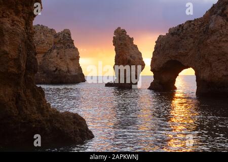 Portugal, Faro District, Lagos, Naturbogen und Küstenfelsen bei Sonnenaufgang Stockfoto