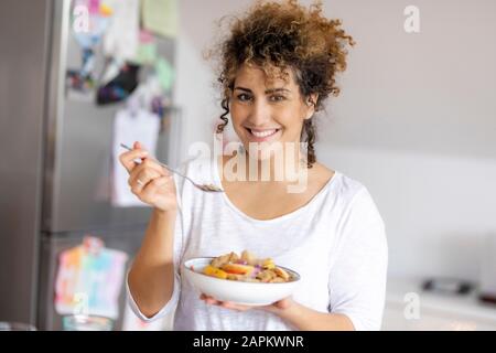 Porträt einer lächelnden Frau mit einer Schüssel mit Fruchtmuesli in der Küche Stockfoto
