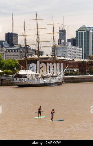 Blick auf ein paar Männer auf Stand Up Paddle Boards auf dem Fluss in Puerto Madero, Buenos Aires, Argentinien Stockfoto